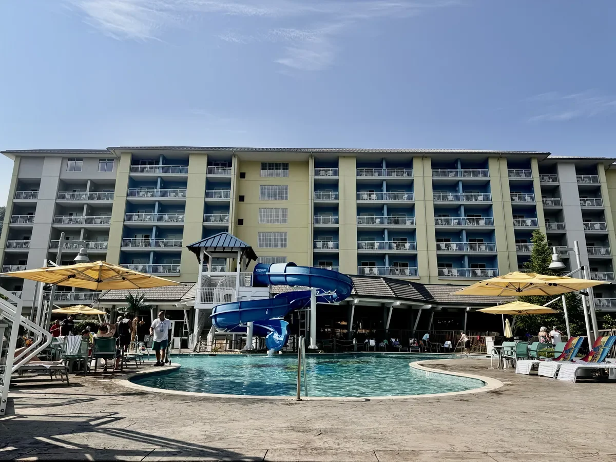 view of outdoor pool with hotel in background. pool has a spiral slide