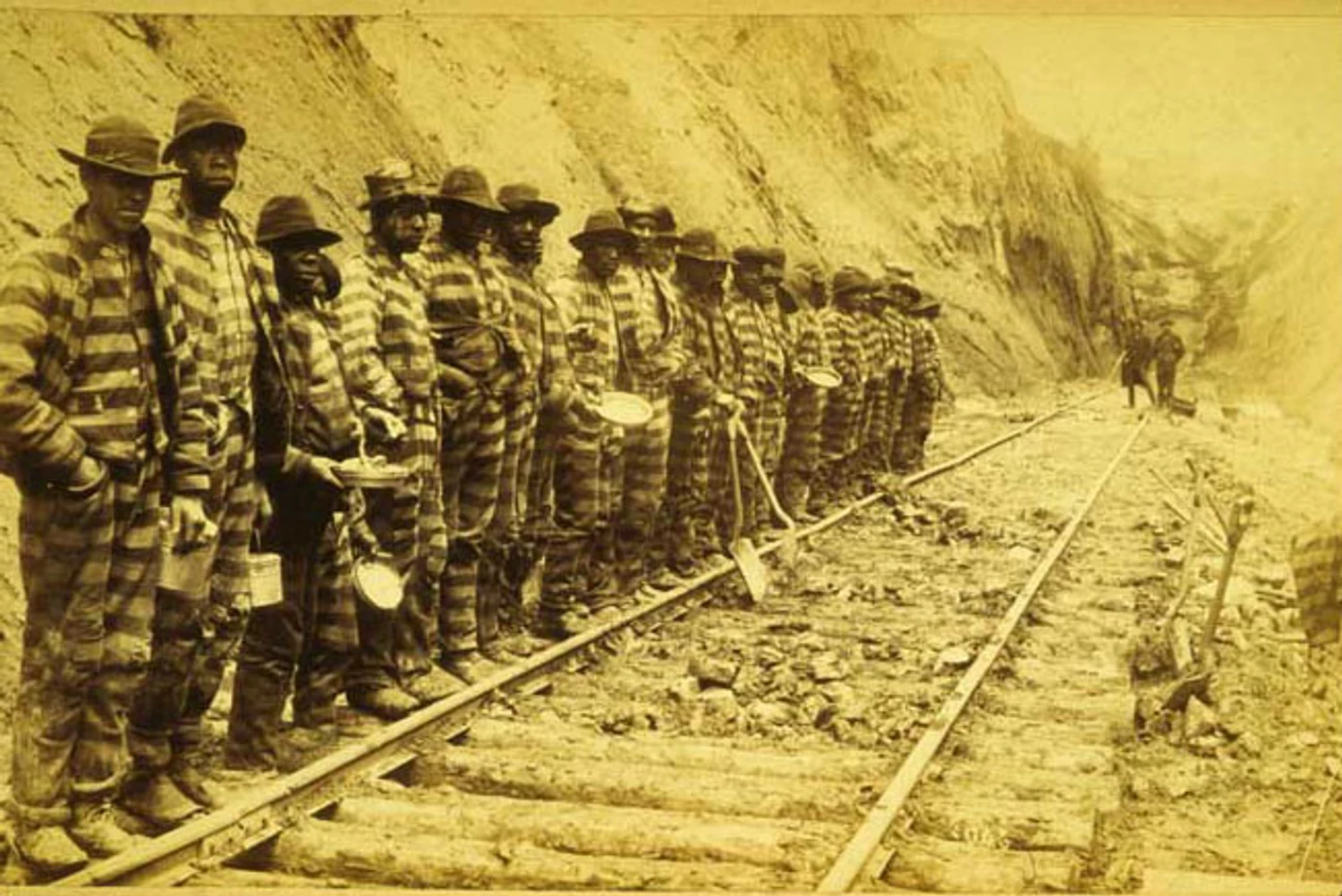 Black incarcerated laborers holding tools and dishes beside Western North Carolina Railroad tracks around 1885