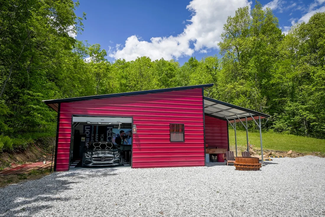 The studio is a custom red metal garage building in the woods outside Robbinsville
