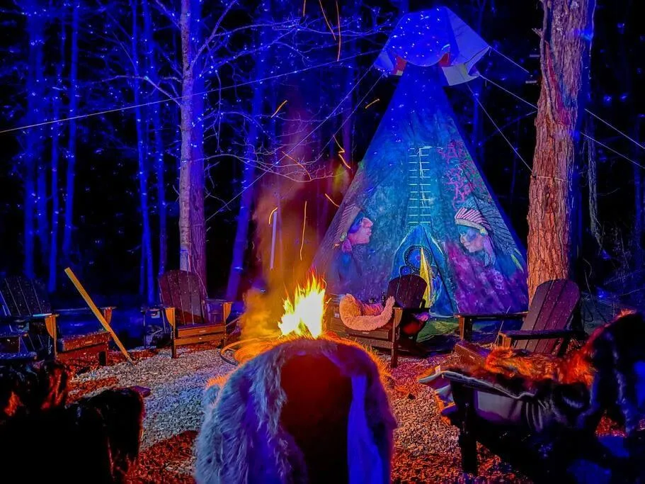 Campfire gathering near illuminated teepee