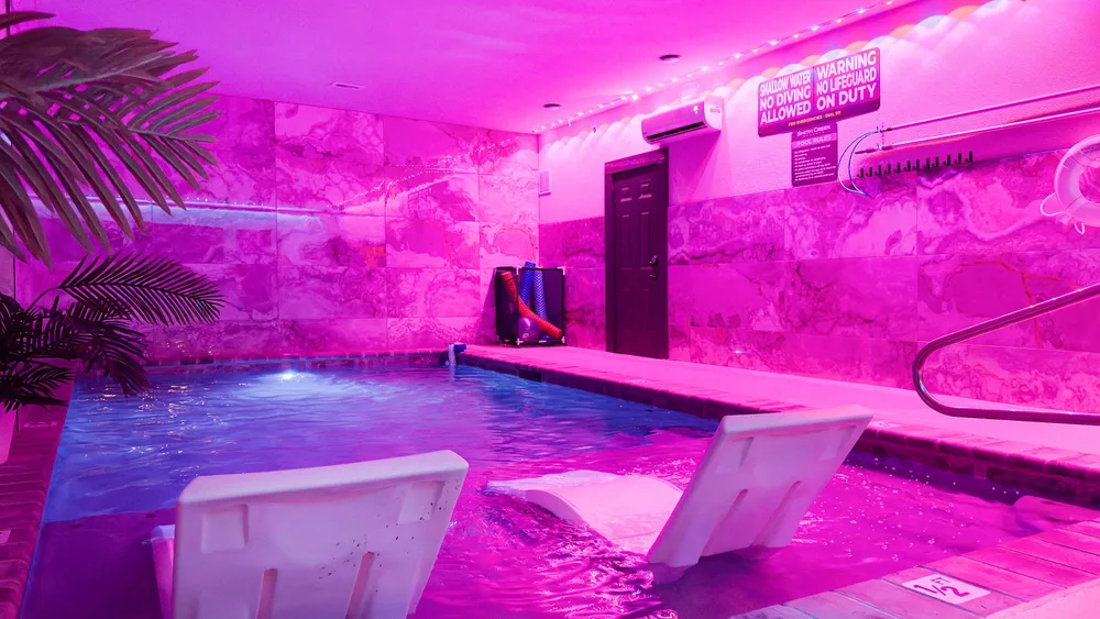 Indoor pool with pink lighting and seating